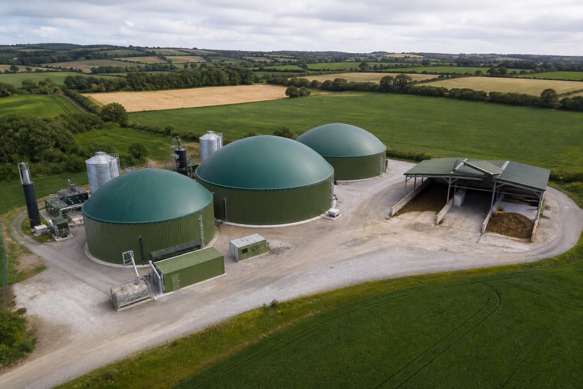 Aerial view of three green-domed anaerobic digester tanks in farmland